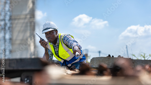 Obraz na płótnie Railway construction supervisor using walkie talkie to coordinate rail installat