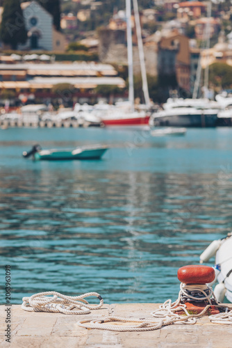 Valokuva Sunlight dances on turquoise waters as boats sway gently in the harbor of a vibrant coastal village during a serene summer day