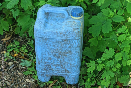 garbage from one old dirty blue dirty  canister stands on the gray ground on the street