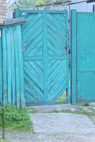 green rural wooden fence wall and closed old door on the street