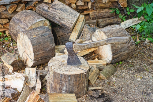 one big old brown axe sticks out of a piece of cut log on the gray ground on a daytime street