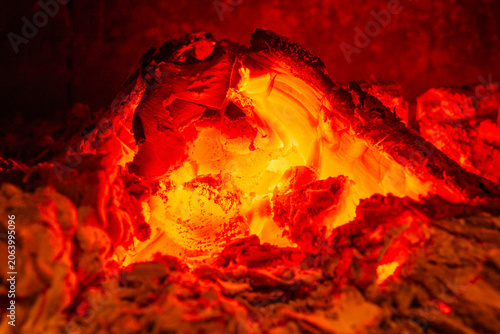 Glowing embers with intense heat and vibrant red-orange hues in a dark setting.