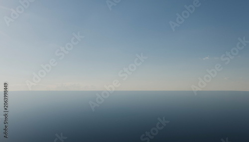 Calm ocean with clear blue sky extending to the horizon under bright daylight.