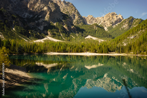 Foto Mountain lake with forest and rocky peaks reflected in clear water