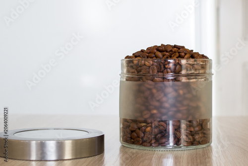 Close up roasted coffee beans in jar container for storage in kitchen in the morning.