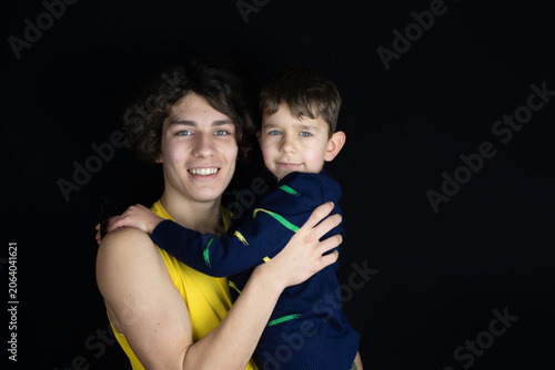 Smiling older brother holds his younger brother in a warm portrait hug, family love, sibling bond and protection. When parents are at work, older son always looks after the younger one