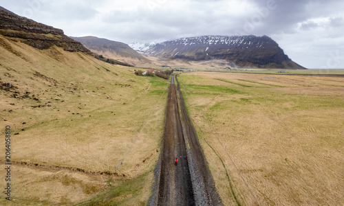 Schilderij op canvas Drone aerial landscape of person in red jacket walking on a long, straight grave
