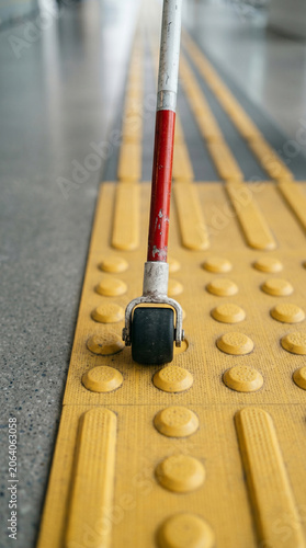 Extreme close-up of a walking stick using a tactile floor indicator for safe navigation, blind person moving through a modern office corridor, accessibility and urban inclusion concept