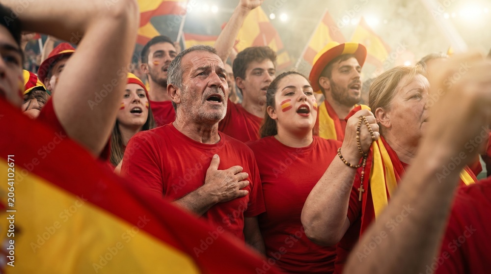 Fototapeta premium Spanish fans in red shirts with face paint singing with flags