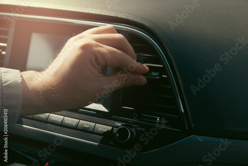 Close-up of a man's hand adjusting the air conditioner in a car