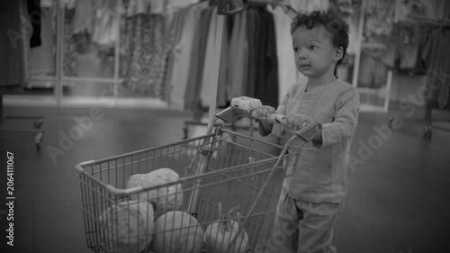 Toddler pushing toy cart in clothing store aisle