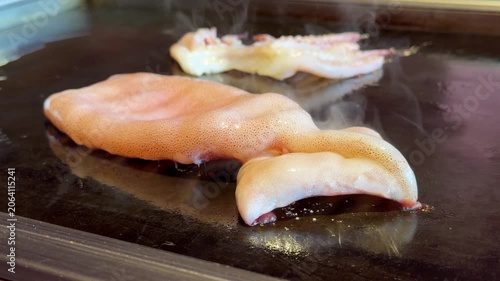 日本の鉄板焼き。イカ焼き。鉄板で焼いてる新鮮なイカとイカゲソの動画。