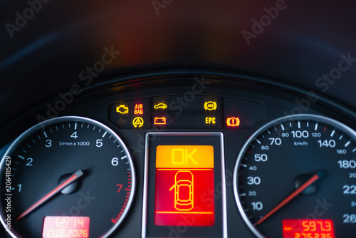 Car dashboard with illuminated warning lights and error indicators. Close-up of a vehicle instrument cluster showing multiple warning symbols.
