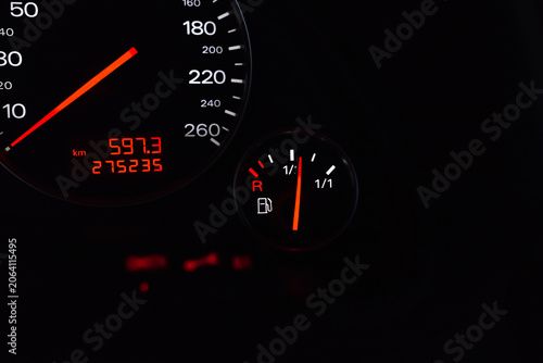 Photos Car fuel gauge and odometer display on a dark dashboard.