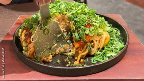 日本のお好み焼き。青ネギと焼きそば麺がたっぷり入った広島お好み焼き。コテでカットする断面動画。