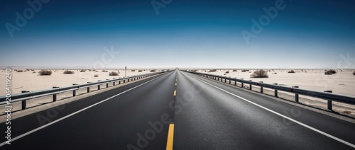Endless highway stretching through a vast desert landscape under a clear blue sky showcasing tranquility and infinity in an arid environment