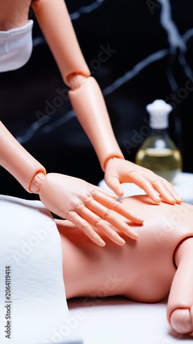 Woman masseur performs massage on client back at spa. Doll models simulate relaxing body treatment session. Professional wellness and skincare care concept layout.