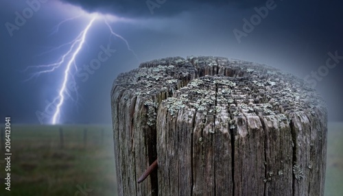 Dramatic Thunderstorm Over Rustic Wooden Post Surrounded by Distant Fields and Striking Lightning in Atmospheric Sky