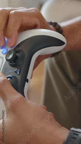 Vertical video: Entering frame hands pressing lit controller buttons, nudging stick at home playing
