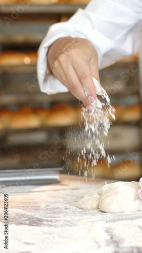 Vertical video: Arm reaching left, dusting flour, baker shaping dough on bench coat bowl for baking