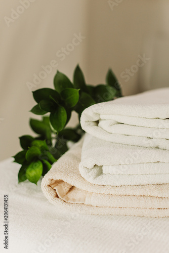 Minimalist still life of luxury spa essentials. White cotton towels with visible textured on a table.