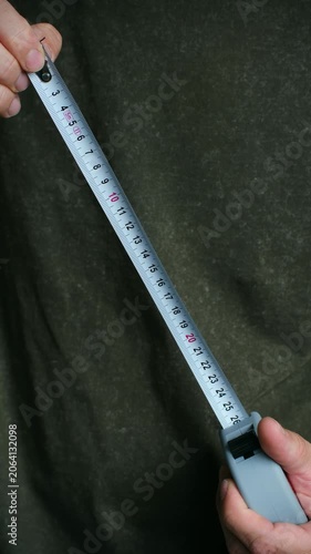 Close up construction worker or handyman holding extending retractable metal tape measure, fundamental tool for accurate measurements in building, renovation projects. Vertical video.