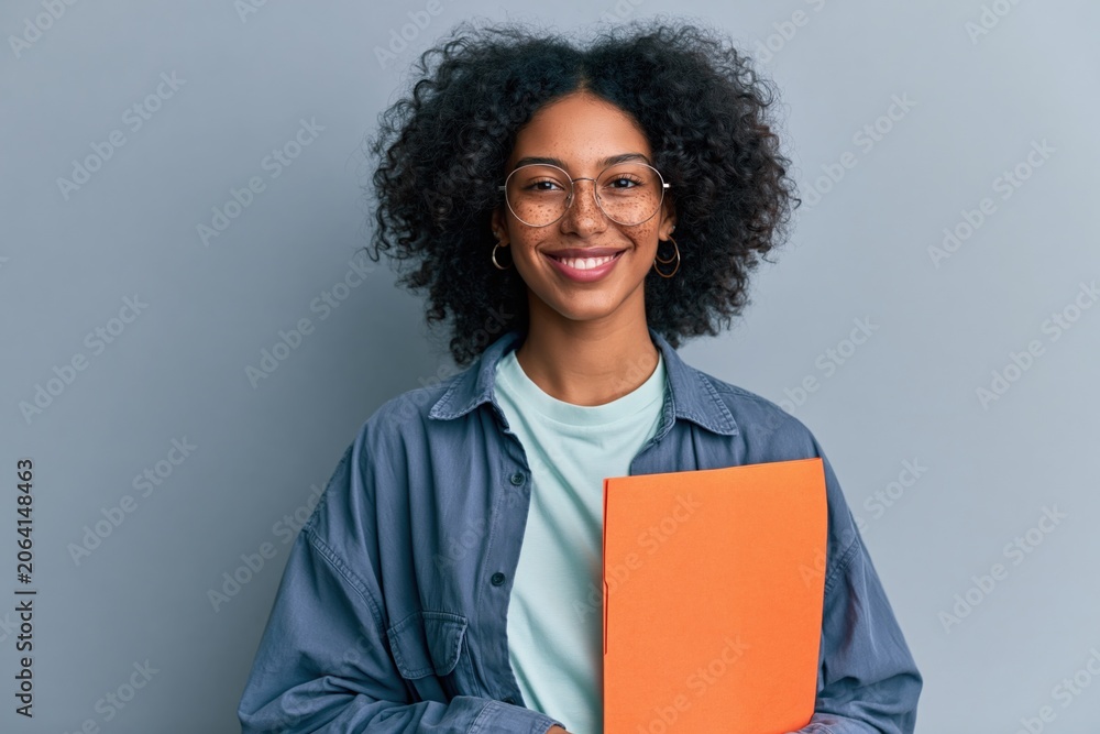 Obraz premium Young student smiling holding an orange folder in a casual jacket for education website banner and portrait background