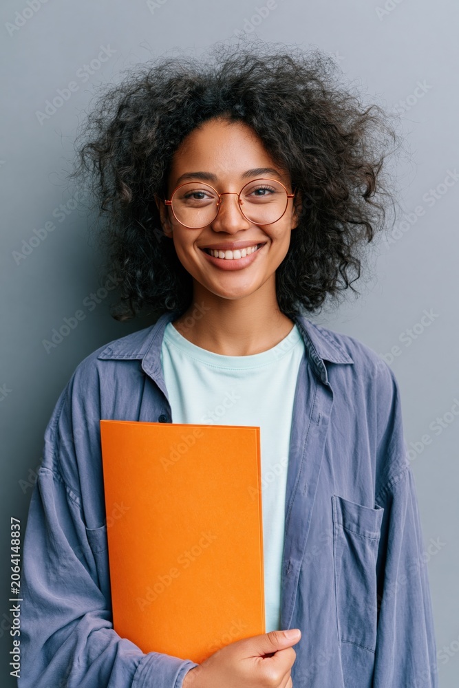 Obraz premium Female student portrait holding an orange folder for education profile and headshot use with friendly smile