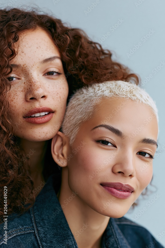 Obraz premium Closeup intimate portrait of diverse women with curly freckled hair and cropped platinum hairstyle for lifestyle banner and editorial background