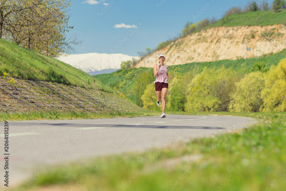 Naklejka premium Young woman jogging on a path