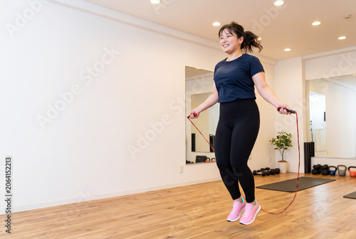 明るいフィットネススタジオで縄跳びをするぽっちゃり体型の女性