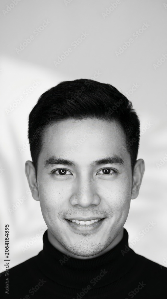 Fototapeta premium Portrait of a smiling young Asian man in a black turtleneck sweater in a studio setting