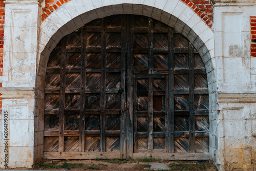 Φωτογραφία Large wooden doors stand closed within an arch made of brick, showing signs of age and wear