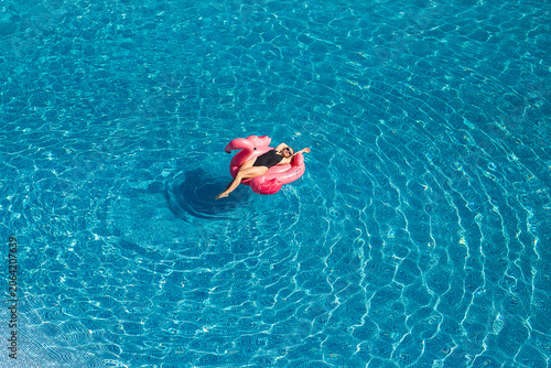 Woman on pool flamingo float. in swimming pool in hotel. Summer holidays, enjoying summer vacations in luxury hotel. Aerial drone view, copy space, space for text