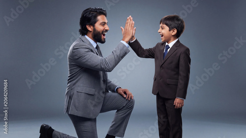 Indian Father And Son Celebrating Success With High Five In Business Mentorship Concept generative ai