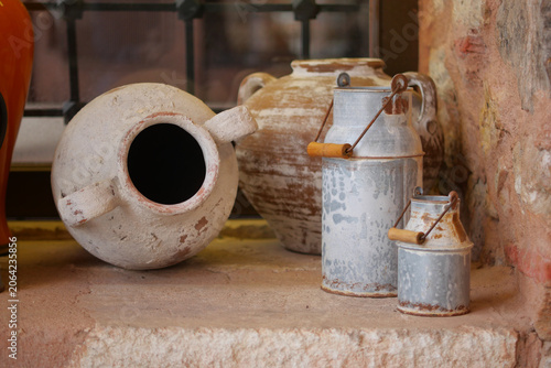 Φωτογραφία Old pottery and milk jugs on a stone shelf in a room