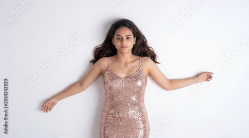 Elegant Indian Woman In Rose Gold Sequin Dress Lying On White Background Fashion Portrait generative ai