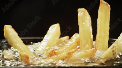 Golden fries sizzling in close up on dark backdrop