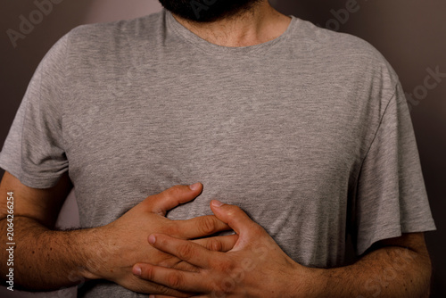 Foto Man clutches his abdomen indicating discomfort or stomach pain.