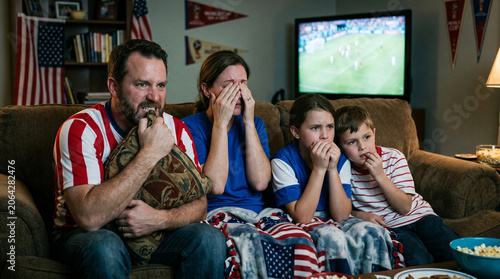 Nervous American family watching a tense soccer match on TV at home
