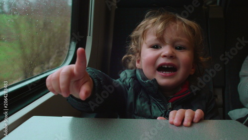 Photos Toddler sitting by train window pointing at desired object then crying in frustr