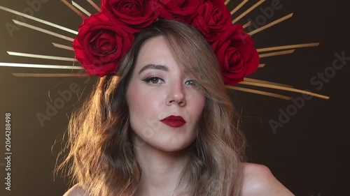 Video. Female portrait. Young adult white woman with bare shoulder, DIY golden halo crown, rose on head, red lips, make up looks at camera on smoke, fog. Diverse beauty, fashion, faith, magic concept 