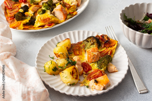 Fotografie Baked potatoes are served with salmon, broccoli, and tomatoes on a plate