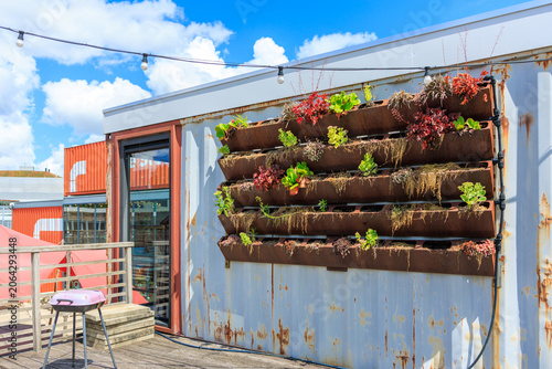 A sleek vertical garden planter mounted on the white corrugated wall of a shipping container office, Startup Village, Amsterdam Science Park