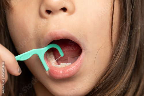 Child using dental flosser while practicing oral hygiene at home