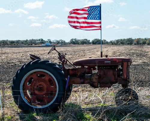 Rusted old tractor with a US flag waving in a Texas field