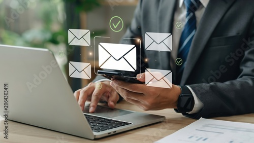 Businessman using smartphone to send multiple digital email messages in the office