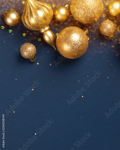 Festive gold Christmas ornament and sparkling glitter on dark blue background. Holiday season celebration concept