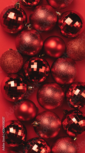 Red Christmas ball ornaments scattered on vibrant red background. Festive holiday decoration