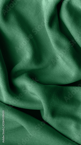 Green fabric texture with soft drapes and folds, textile background
